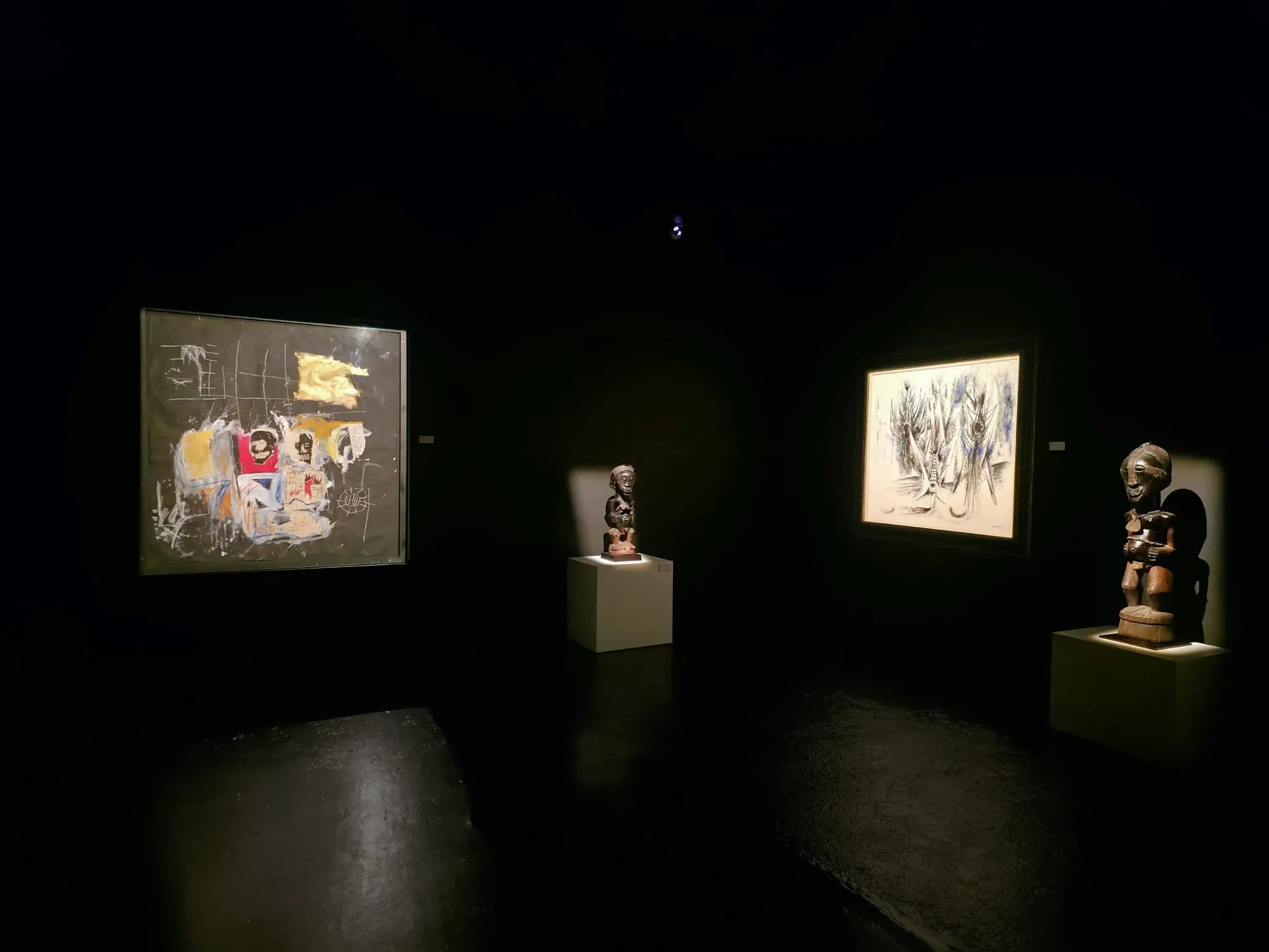 Jean-Michel Basquiat and Wifredo Lam paintings displayed with Songye sculptures