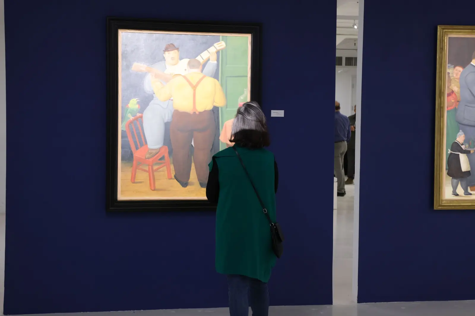 A visitor viewing a Fernando Botero painting in the Botero & Music exhibition.