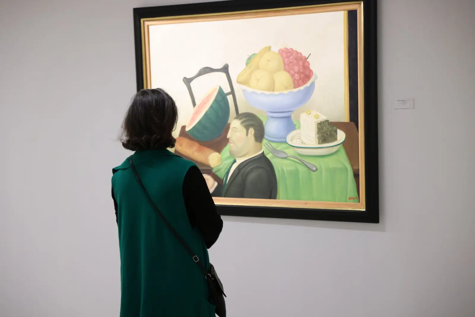 A visitor looking at a Fernando Botero still life in the Botero & Music exhibition.