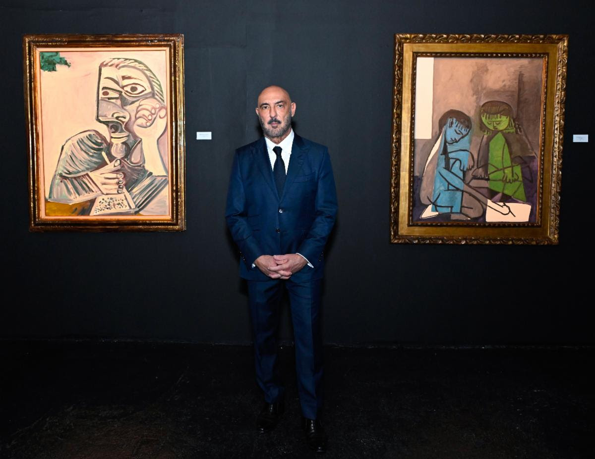 Gary Nader standing between two framed Picasso paintings at Gary Nader Art Centre.