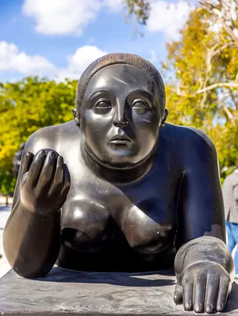 Detail of a reclining bronze figure framed by trees at Nader Sculpture Park.