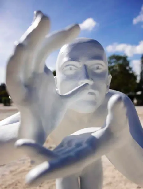 Close-up of a white figurative sculpture with a raised arm.