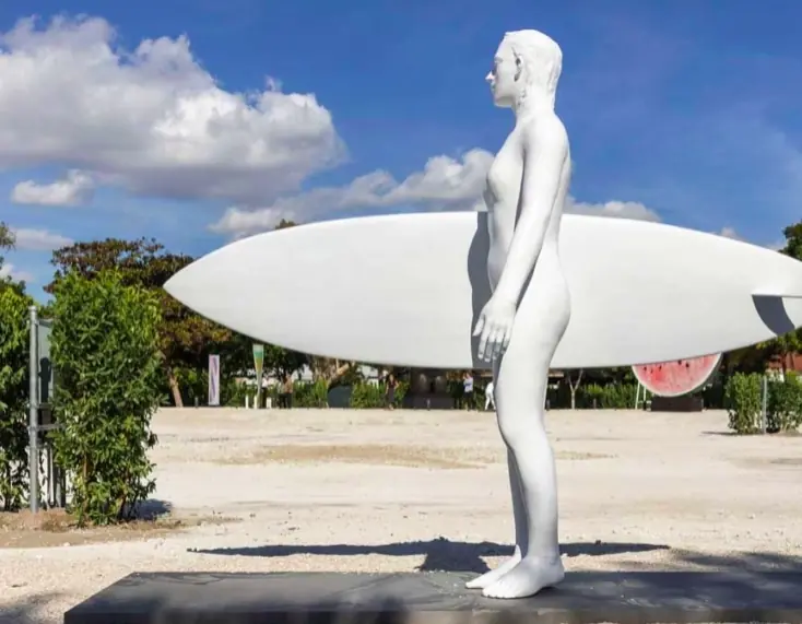 White figurative sculpture with a surfboard in the open-air collection.