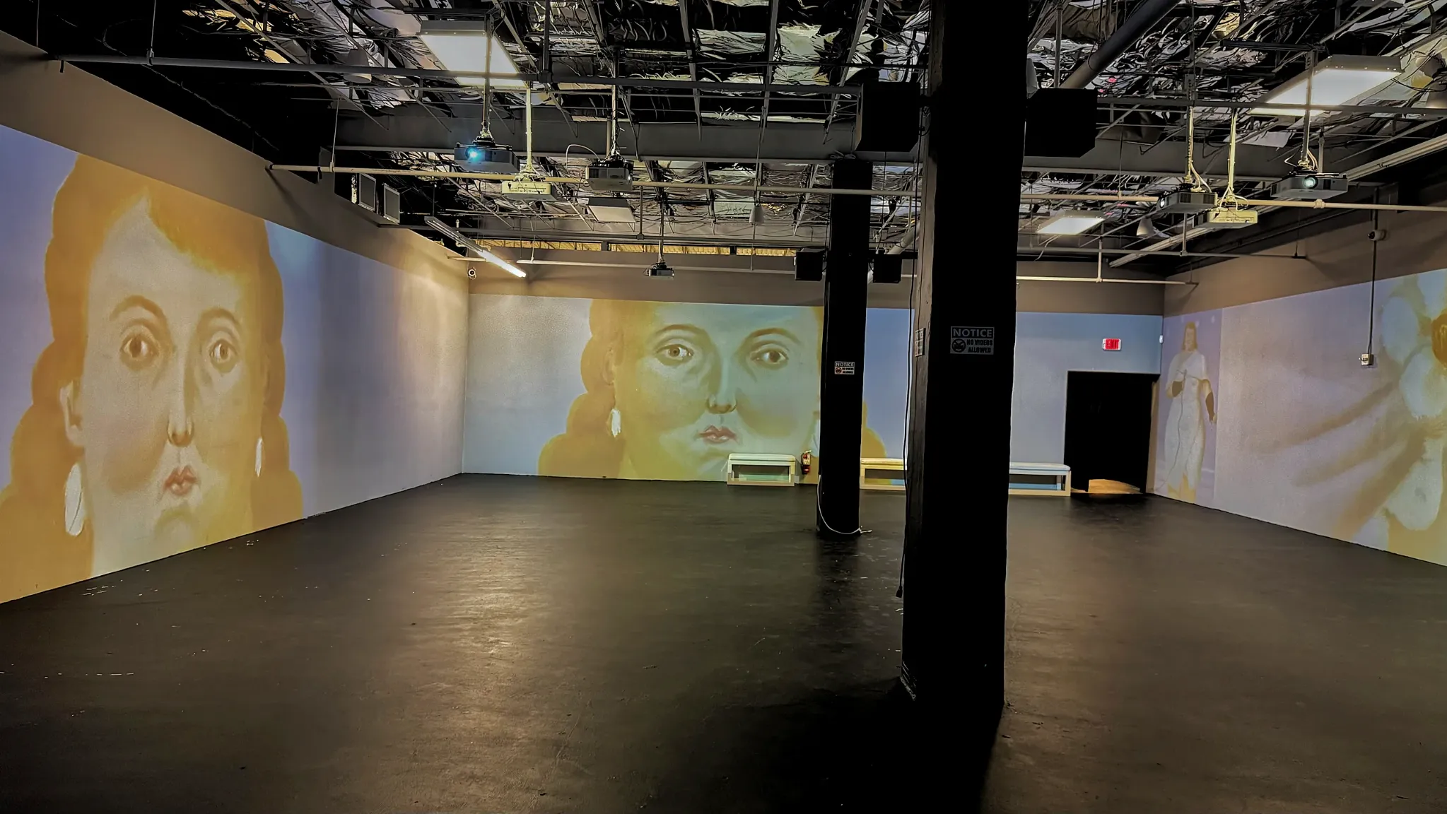 Panoramic view of the Botero Immersed room with portraits projected on surrounding walls